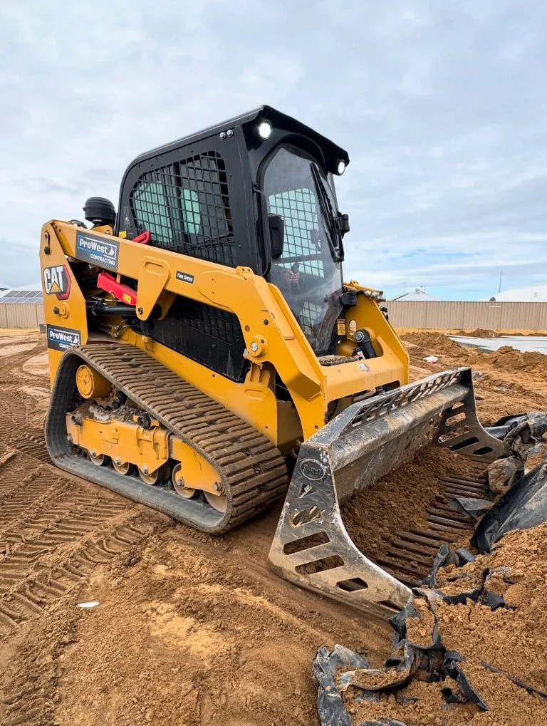 ProWest-branded Cat posi-track with a rock grapple bucket on a sand pad