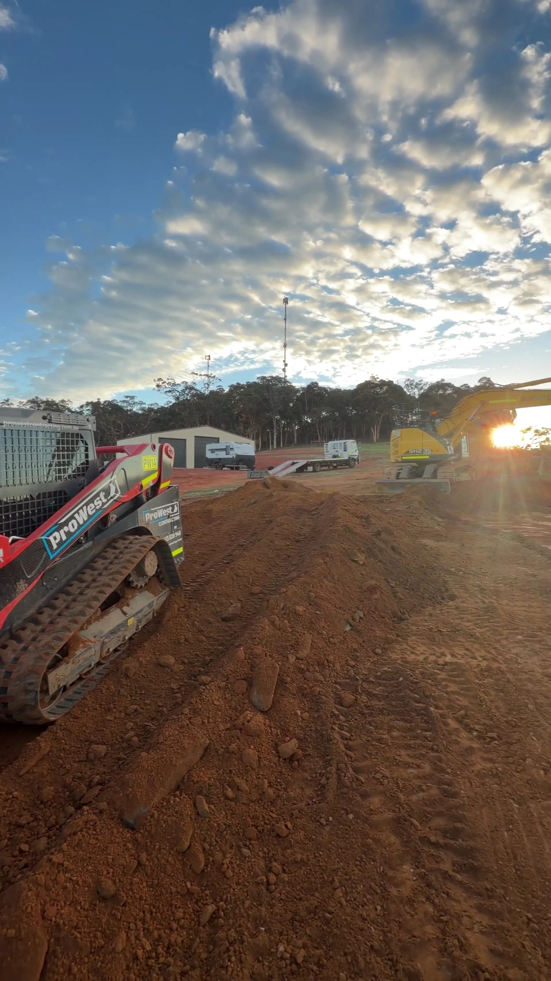 Newly formed access road at sunrise with a ProWest posi-track working the surface