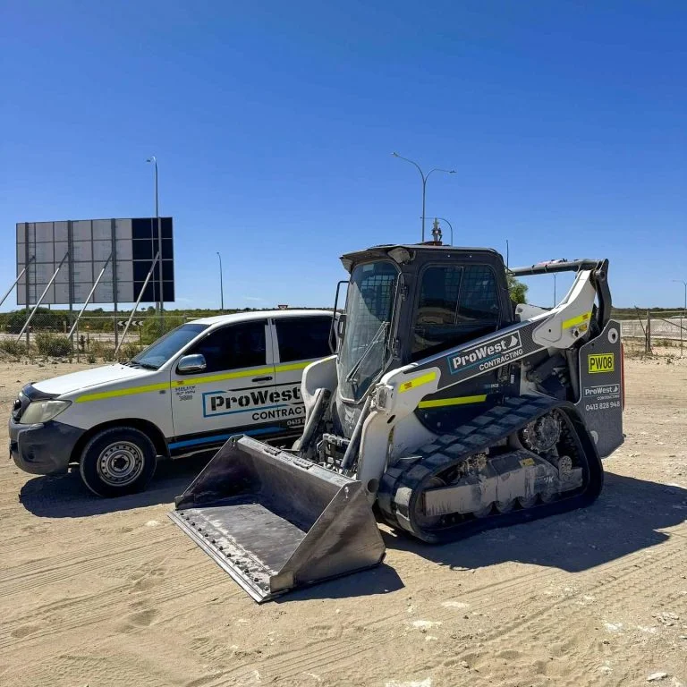 ProWest posi-track PW08 and Hilux ute parked on a sandy roadside site under a clear sky