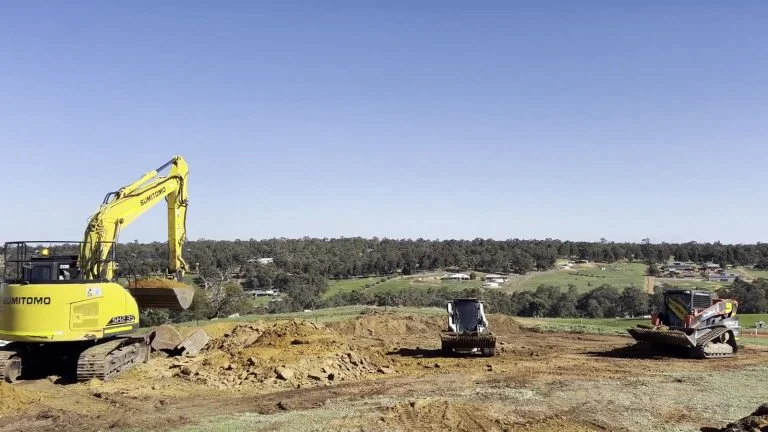Siteworks in progress with an excavator, posi-track and tipper truck on site